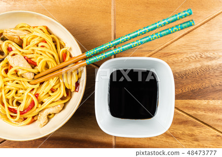 Chicken chow mein and chopsticks on wooden table Chicken chow mein and chopsticks on wooden table 48473777