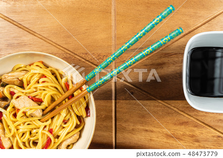 Chicken chow mein and chopsticks on wooden table Chicken chow mein and chopsticks on wooden table 48473779