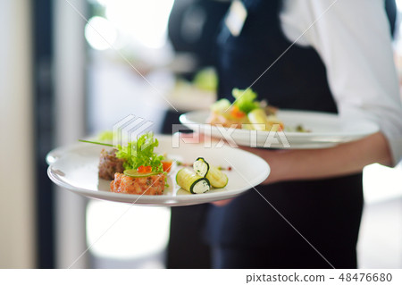 Waiter carrying plates with meat dish  48476680