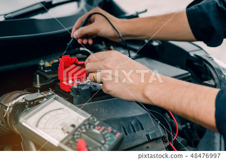 Car mechanic is using the car battery meter Car mechanic is using the car battery meter 48476997