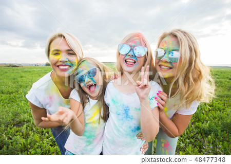 Friendship, holidays, color concept - friends smiling and having fun in colors on the festival of 48477348