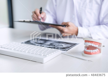 Male doctor or dentist writing report working with tooth x-ray f Male doctor or dentist writing report working with tooth x-ray f 48483675