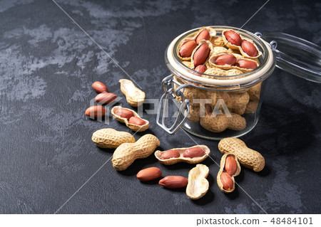 Peanut in an open glass jar on a black table. Peanut in an open glass jar on a black table. 48484101