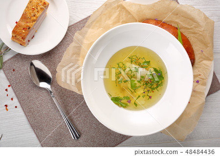 chicken soup with bread in white plate on a white wooden background chicken soup with bread in white plate on a white wooden background 48484436