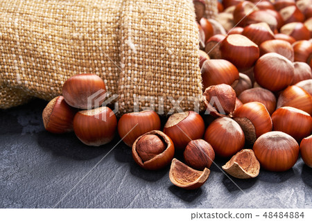 Hazelnut in burlap sack on black stone background 48484884