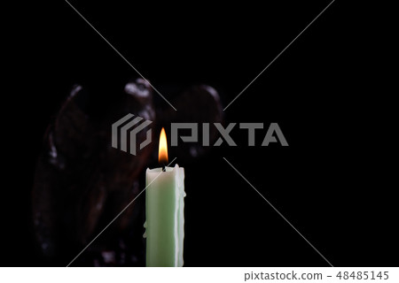 Burning candle illuminates blurred figure Burning candle illuminates blurred figure 48485145