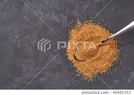 Brown sugar in a metal spoon on a black table Brown sugar in a metal spoon on a black table 48485352
