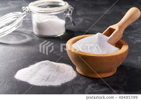 Wooden bowl with baking soda on a black background 48485399