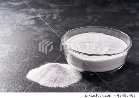 Glass bowl of baking soda on a black background. Glass bowl of baking soda on a black background. 48485402