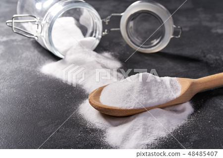 Baking soda in a wooden spoon on a black table Baking soda in a wooden spoon on a black table 48485407
