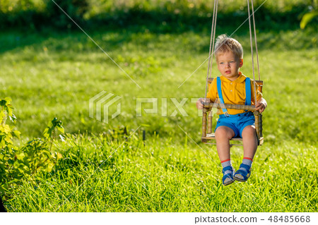 Rural scene with toddler boy swinging outdoors. Rural scene with toddler boy swinging outdoors. 48485668