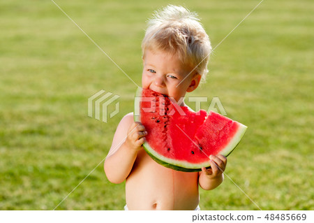 One year old baby boy eating watermelon in the garden One year old baby boy eating watermelon in the garden 48485669