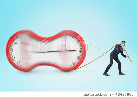 Businessman pulling a stretched clock with a rope on blue background Businessman pulling a stretched clock with a rope on blue background 48485993