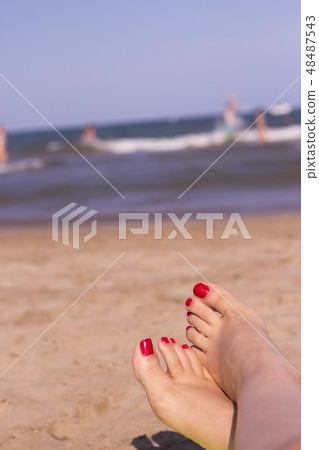 Feet of woman with nails painted red on the sand Feet of woman with nails painted red on the sand 48487543