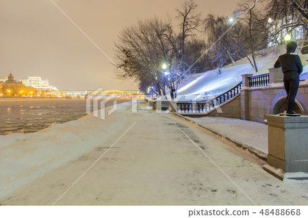 The road in the snow drifts near the river in the park in the evening The road in the snow drifts near the river in the park in the evening 48488668