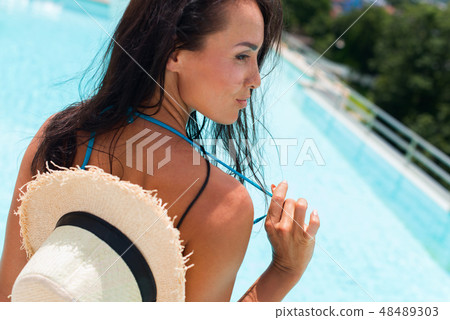 Happy brunette suntanned woman in blue swimsuit 48489303