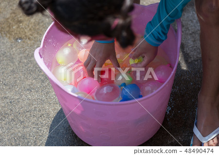 A girl holding a water balloon 48490474