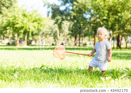 Sweet kid trying to catch butterflies in the garden Sweet kid trying to catch butterflies in the garden 48492170