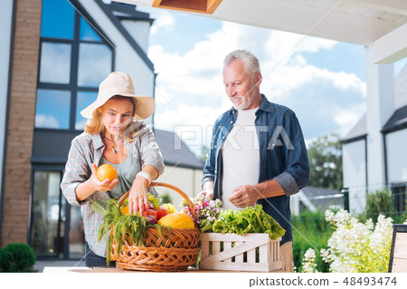 Appealing housewife holding nice fresh orange after buying food with husband 48493474