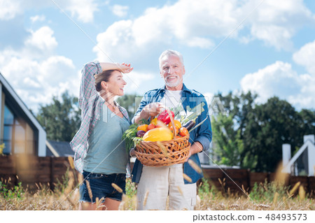 Smiling blonde-haired wife feeling satisfied after gathering harvest with husband 48493573