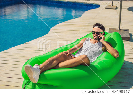 Young man enjoying leisure, lying on the air sofa Lamzac, near the pool Young man enjoying leisure, lying on the air sofa Lamzac, near the pool 48498947