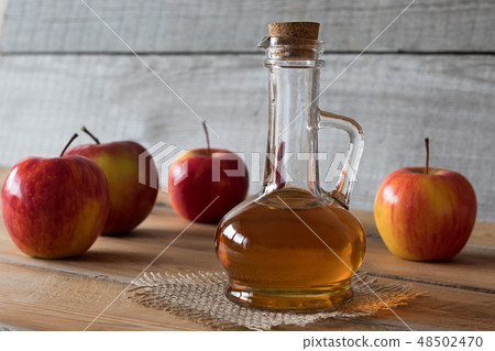 A bottle of apple cider vinegar with apples 48502470
