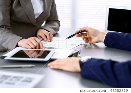 Business people and lawyer discussing contract papers sitting at the table, hands close-up. Teamwork Business people and lawyer discussing contract papers sitting at the table, hands close-up. Teamwork 48502819