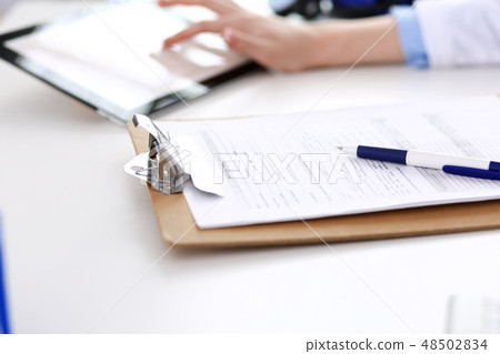 Doctor working table. Woman physician using tablet computer while sitting in hospital office close 48502834