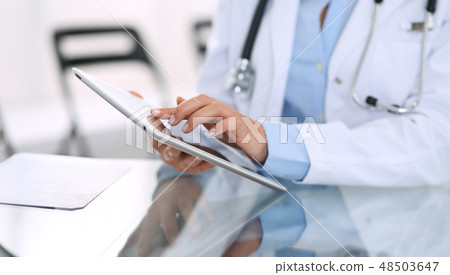 Female doctor hands using digital tablet while sitting at glass desk at hospital office. Medicine Female doctor hands using digital tablet while sitting at glass desk at hospital office. Medicine 48503647