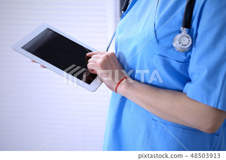 Woman doctor using tablet computer while standing straight in hospital office, closeup. Healthcare Woman doctor using tablet computer while standing straight in hospital office, closeup. Healthcare 48503913