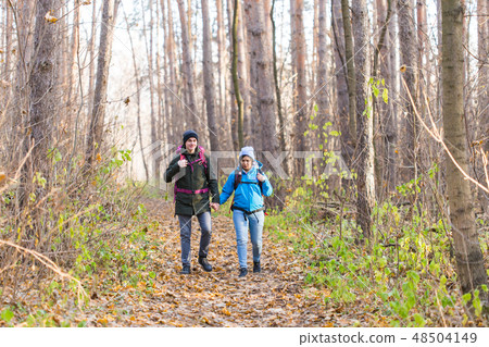 Travel, tourism, hike and nature concept - Tourists walking in park with backpack dressed in blue 48504149