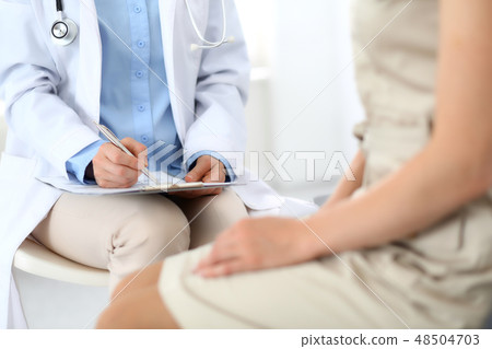 Doctor and patient talking. Physician at work in hospital while writing up medication history Doctor and patient talking. Physician at work in hospital while writing up medication history 48504703