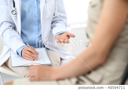 Doctor and patient talking. Physician at work in hospital while writing up medication history Doctor and patient talking. Physician at work in hospital while writing up medication history 48504711