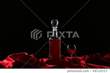 glass and bottle of wine on a dark background silk 48510317
