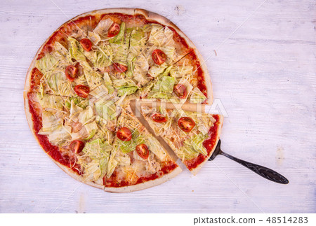 Chicken breast and lettuce leaves pizza is served  48514283