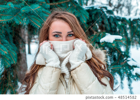 Beautiful girl covers her face with a scarf, expressive look. In winter, in the city park against 48514582