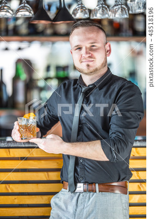Bartender standing before the bar with drink. 48518196