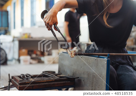 A glassblower student tries to make a flower out of glass A glassblower student tries to make a flower out of glass 48518535