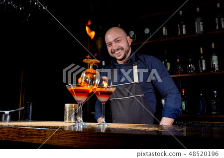 Fiery show at the bar. The bartender makes hot alcoholic cocktail and ignites bar. Bartender 48520196