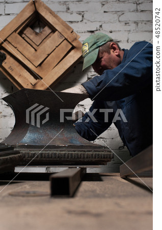 Blacksmith in workshop soldering metal object Blacksmith in workshop soldering metal object 48520742