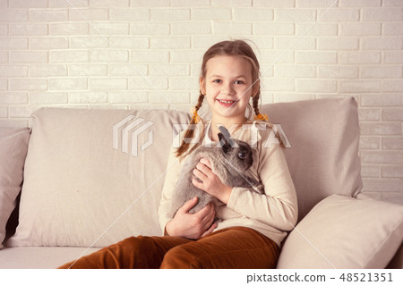 Portrait of happy girl with rabbit indoors 48521351