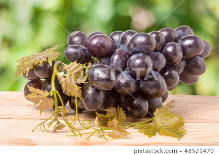 bunch of blue grapes on a wooden table with blurred background bunch of blue grapes on a wooden table with blurred background 48521470
