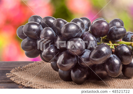 bunch of blue grapes on a wooden table with blurred background bunch of blue grapes on a wooden table with blurred background 48521722
