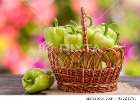 green bell peppers in a wicker basket on  wooden table with  blurred background 48521753