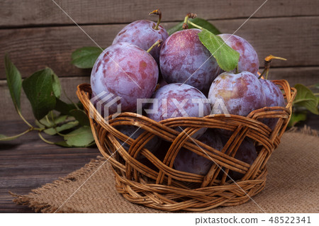 plum in a wicker basket on the wooden background with sackcloth 48522341