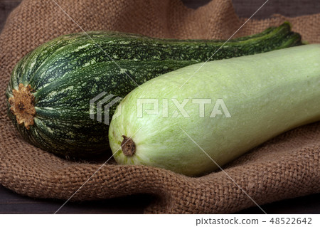 green zucchini and courgette on sackcloth  wooden background 48522642