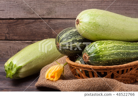 green zucchini and courgettes with a flower on sackcloth wooden background green zucchini and courgettes with a flower on sackcloth wooden background 48522766