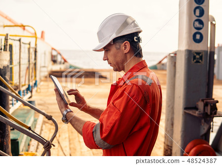 chief officer or captain on deck of vessel or ship watching digital tablet 48524387