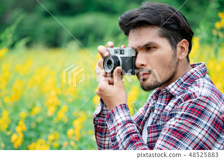 Young hipster man taking photo with retro camera. 48525883