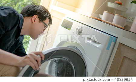 Asian technician looking into washing machine Asian technician looking into washing machine 48529934